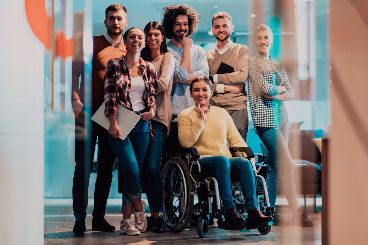 imagine ce prezinta un grup de persoane inclusiv o persoana cu dizabilitati formand un grup fericit care colaboreaza impreuna